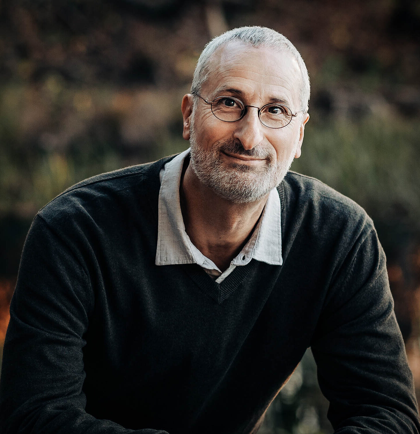 Jonathan Stein seated outdoors, smiling gently