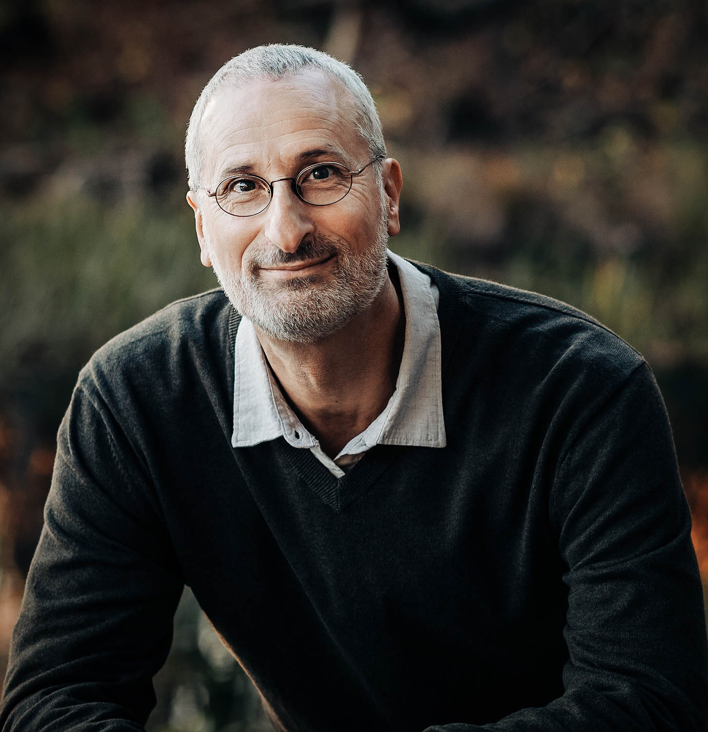 Jonathan Stein seated outdoors, smiling gently