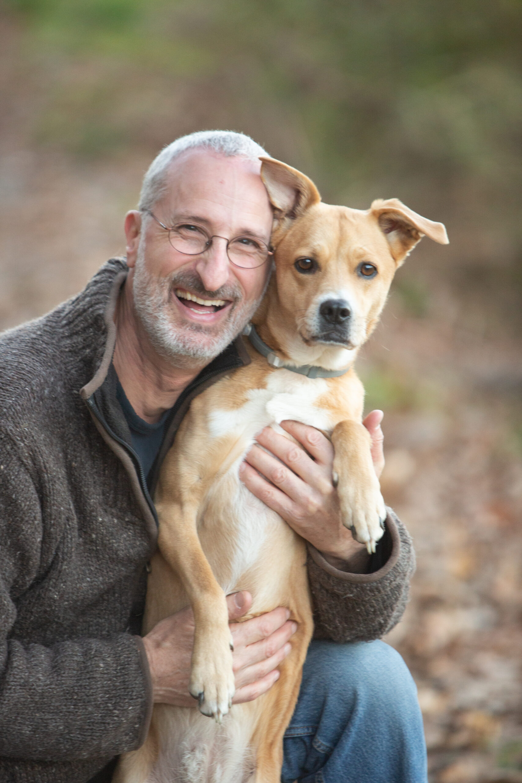 Jonathan Stein with His Dog Jonathan Stein smiling while holding his tan-and-white dog outdoors.